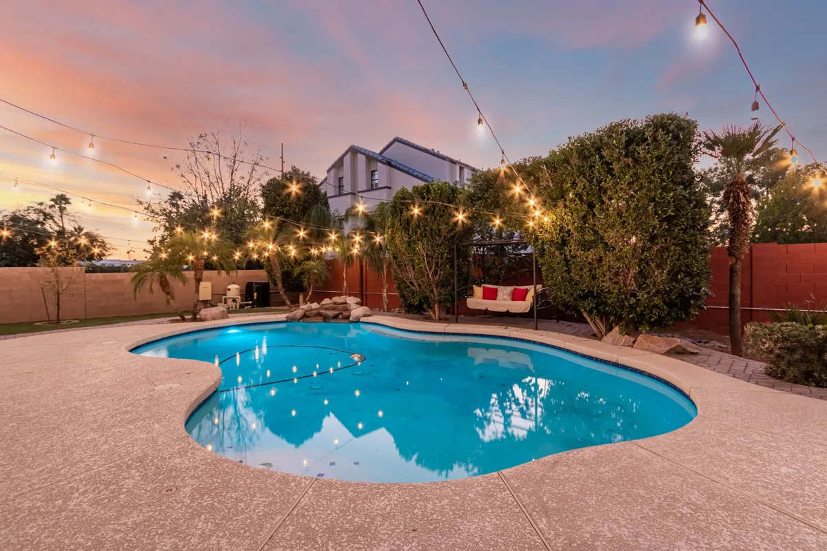 The backyard showcases a sparkling swimming pool, hanging lights, and a comfortable seating area, set for relaxation or evening gatherings. This scene encapsulates the Arizona lifestyle and spaces for unwinding after work or engaging with friends and family.
