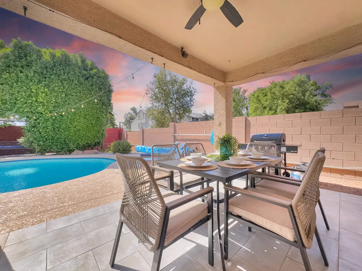 A stylish outdoor dining table set with dishes sits beside a shimmering pool and a built-in grill, ready for an alfresco dinner or barbecue with friends. The surrounding atmosphere is relaxed and social, perfect for sharing meals and stories after a day of Mesa adventures.