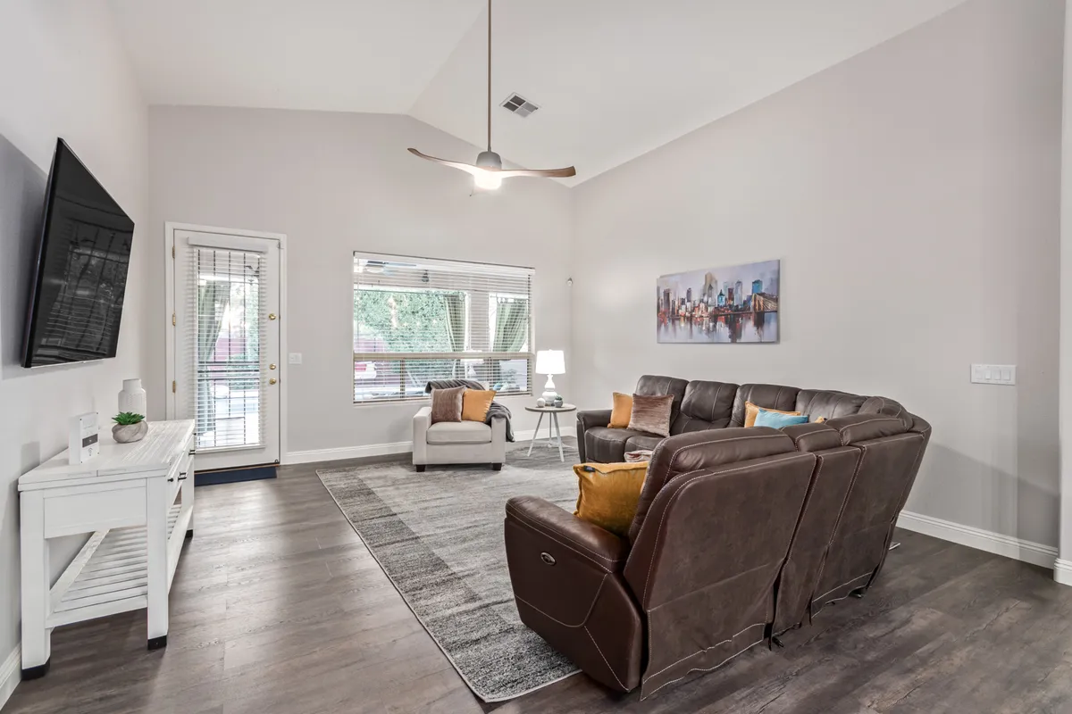 A cozy interior space bathed in natural light, featuring a comfortable brown leather sofa, large windows, and a modern art piece. The room feels both welcoming and functional, ideal for relaxing or working remotely—all complemented by strong Wi-Fi connectivity.